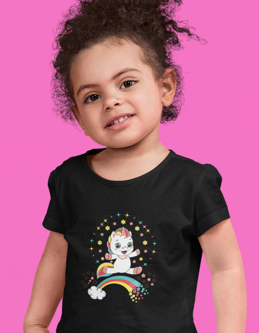 Fantasy Clothing. Little Girl Wearing A Black T-shirt Featuring A Unicorn Jumping Over A Rainbow.