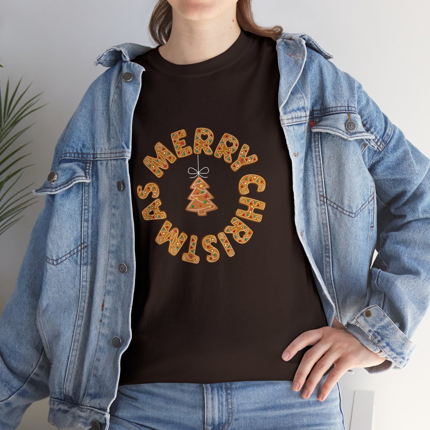 Holiday, Christmas. A woman is wearing a Christmas t-shirt with a wreath made out of gingerbread cookies and spells out Merry Christmas. A Christmas tree cookie dangles in the middle of the wreath.