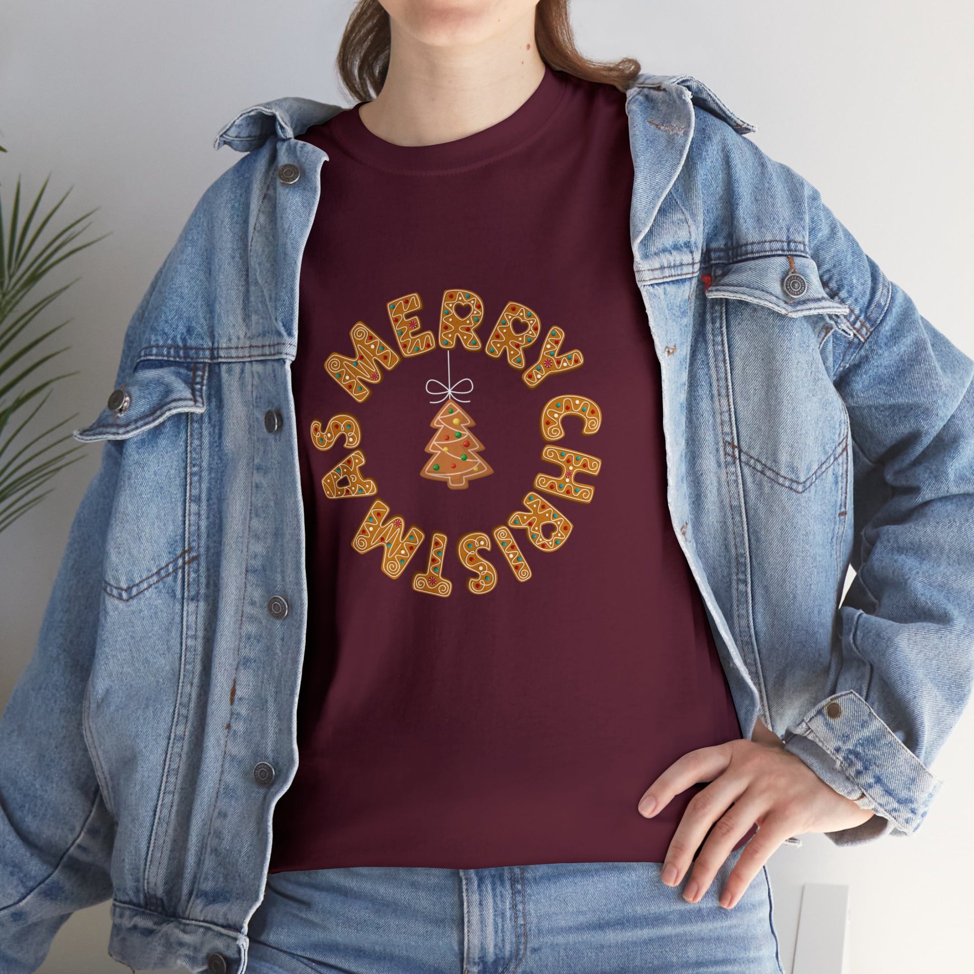 Holiday, Christmas. A woman is wearing a Christmas t-shirt with a wreath made out of gingerbread cookies and spells out Merry Christmas. A Christmas tree cookie dangles in the middle of the wreath.